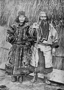 Ainu-koppel buiten het traditionele Ainu-huis van een rietgedekte hut, eind 19e eeuw